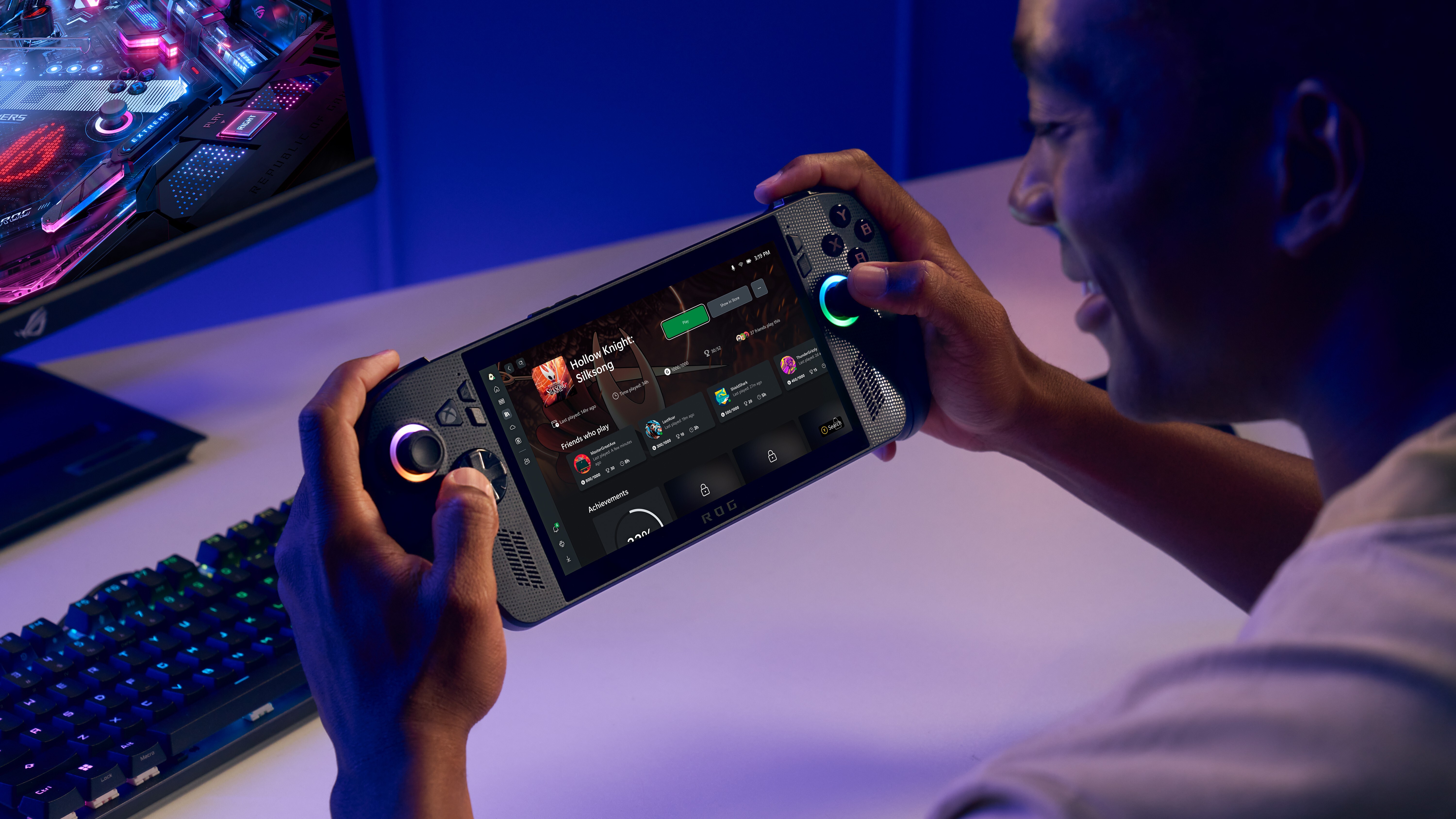 A promotional image for the ROG Xbox Ally X, demonstrating the handheld PC with a full gaming desktop nearby.